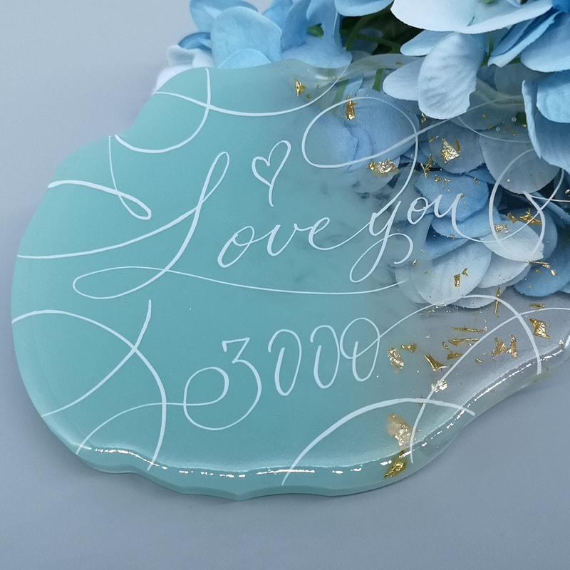 White calligraphy on a pale blue floral acrylic disc