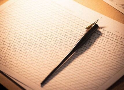 A calligraphy dip pen resting on grid practice paper