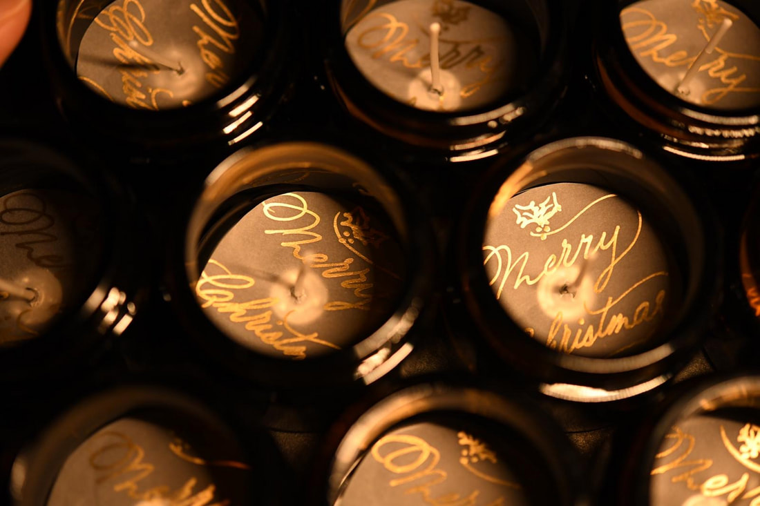Dark cosmetic jar lids hand-lettered with gold calligraphy